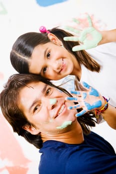 Portrait of a girl showing paint on her palms with her father smiling