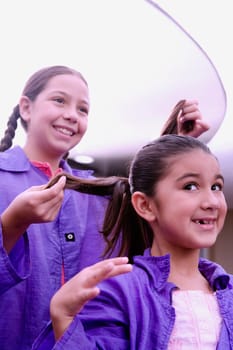 Close-up of a girl making braids of another girl
