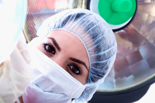 Portrait of a female surgeon in a surgical cap and surgical mask