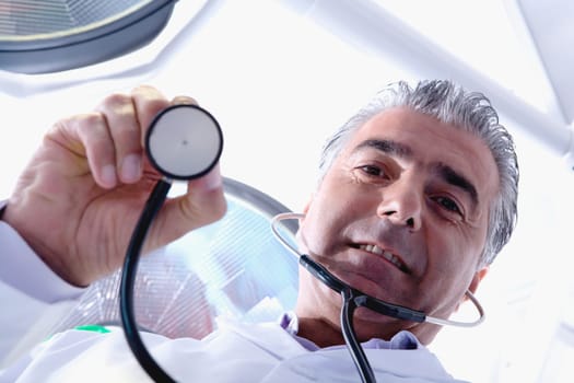 Low angle view of a male doctor holding a stethoscope
