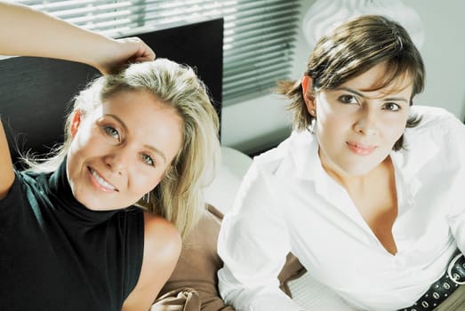 High angle view of two mid adult women reclining on the bed