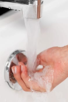 Close-up of a man washing his hands in the bathroom sink