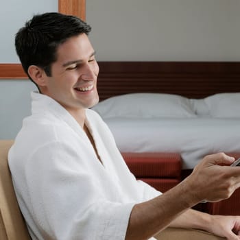 Side profile of a young man holding a remote control and smiling