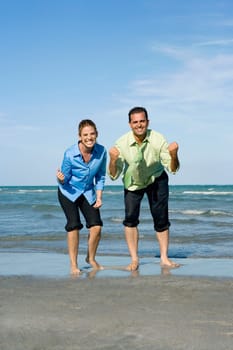 Mid adult couple clenching their fists on the beach