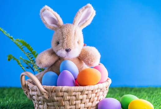 Easter bunny toy and Easter eggs in basket on green grass