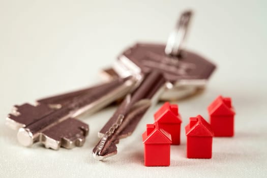 Red miniature houses and bunch of keys. Real estate concept.