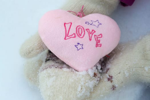 Pink heart in white warm wool gloves close up