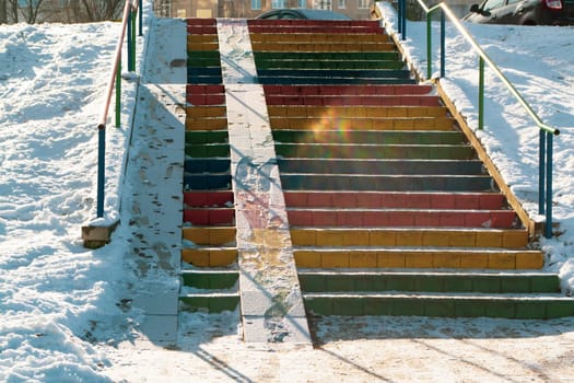 Snowy background with concrete stairs painted in the rainbow colors