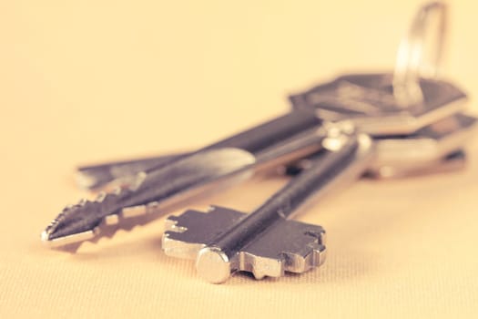 Bunch of keys lying on yellow background. Filtered image.