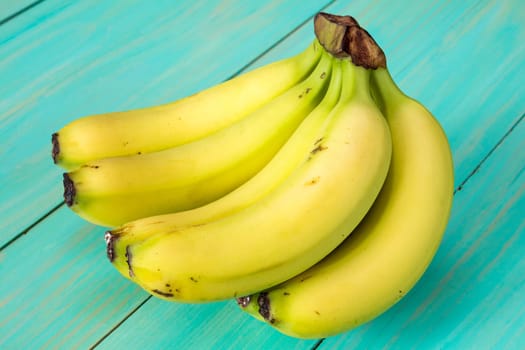 Bunch of healthy bananas on blue painted wooden background