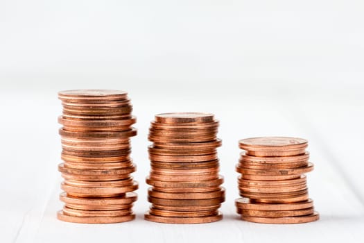 Three stacks of copper coins on white wooden background