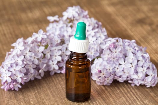Essential aroma oil with lilac on wooden background