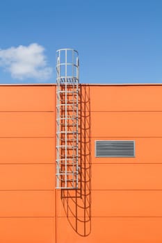 Modern industrial building wall with metal ladder,under blue sky