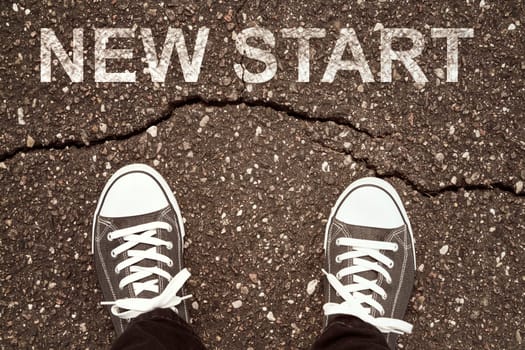 Man standing on cracked asphalt with NEW START sign