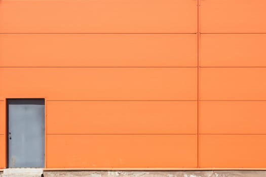 Modern orange building wall with metal doors