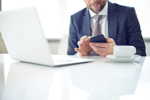 Man sitting on table and typing message on phone