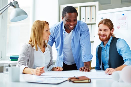 Three business people planning over blueprint