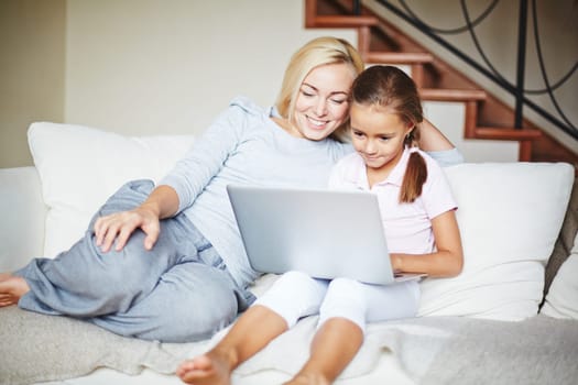 Smiling mother and daughter using laptop at home