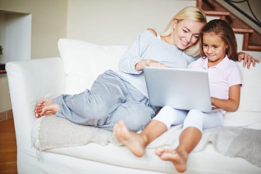Mother pointing to computer and daughter looking at laptop and smiling