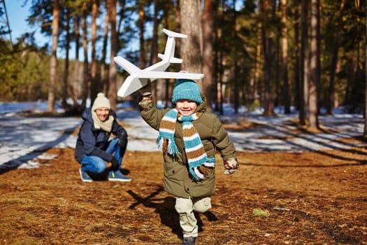 Little boy running with toy plane and his father looking at him