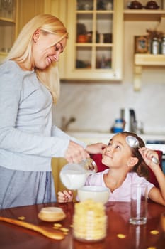 Daughter looking at mother and waiting for her milk and cornflakes