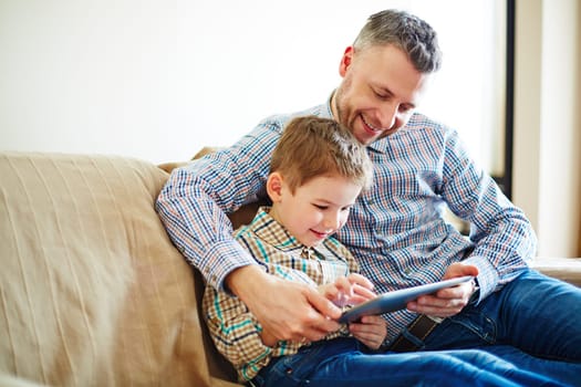 Father and son looking at tablet and smiling