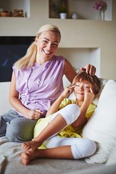 Little daughter making grimace and mother laughing at her