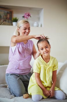 Mother making hairstyle for her daughter