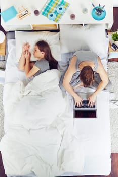 Man working on laptop whiles his girlfriend sleeping