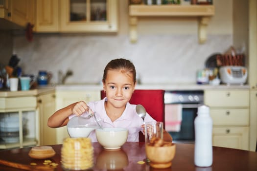 Girl pouring milk and looking at camera