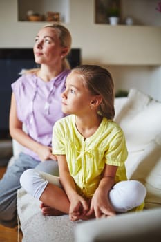 Two members of family looking at sideway and sitting on sofa