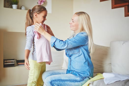 Careful mother fitting clothes on her daughter