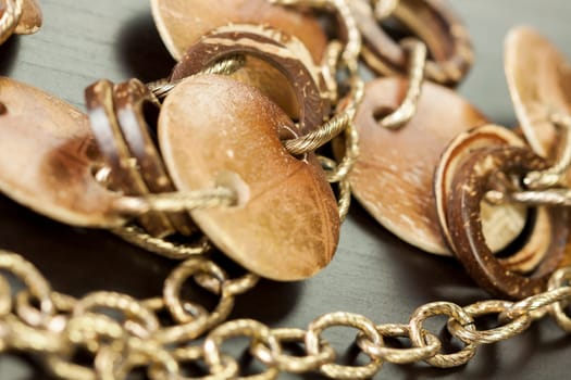 Bracelet or necklace with copper colored round pendants as close-up on dark background