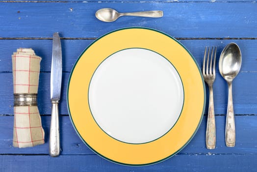 plate with silver cutlery on an old blue table