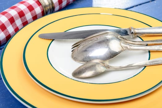 plate with silver cutlery on an old blue table