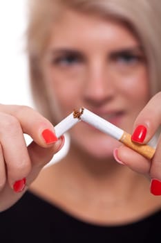 Young blonde woman breaks a cigarette stops smoking isolated against white background