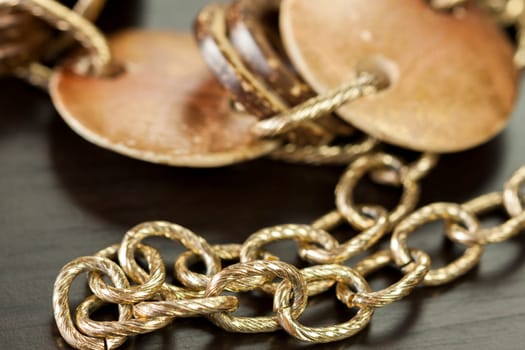 Bracelet or necklace with copper colored round pendants as close-up on dark background