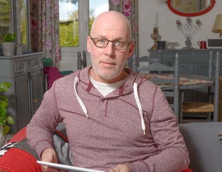 a senior man with a digital tablet on the sofa