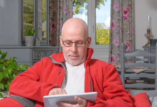 a senior man with a digital tablet on the sofa