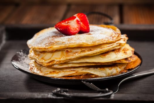 Pancakes or crepes with fresh strawberries and powdered sugar
