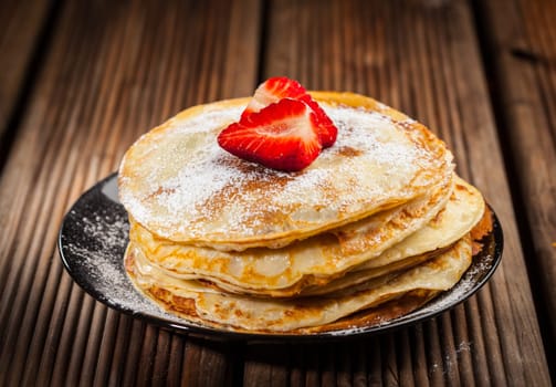 Pancakes or crepes with fresh strawberries and powdered sugar