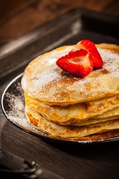 Pancakes or crepes with fresh strawberries and powdered sugar