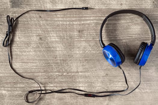 Blue headphones on wooden background with copy-space