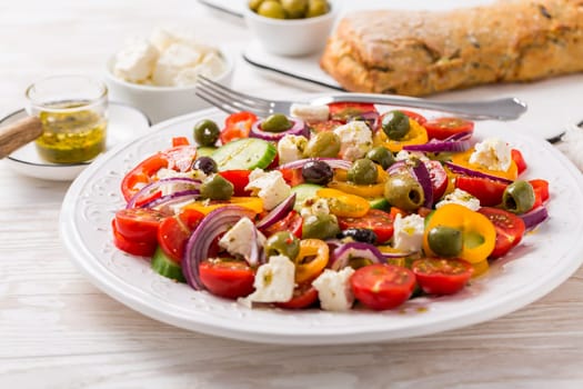 Greek salad of fresh cucumber, tomato, sweet pepper, lettuce, red onion, feta cheese and olives with olive oil dressing. Healthy food