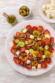 Greek salad of fresh cucumber, tomato, sweet pepper, lettuce, red onion, feta cheese and olives with olive oil dressing. Healthy food, top view