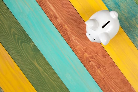 Piggy bank on color wooden background, top view
