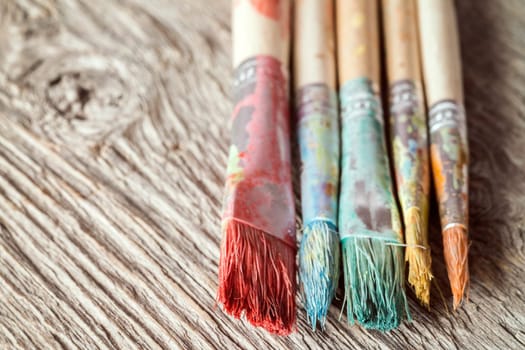 Close-up view of dirty paint brushes on wooden background, selective focus