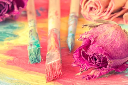 Abstract painting with dry roses and paint brushes