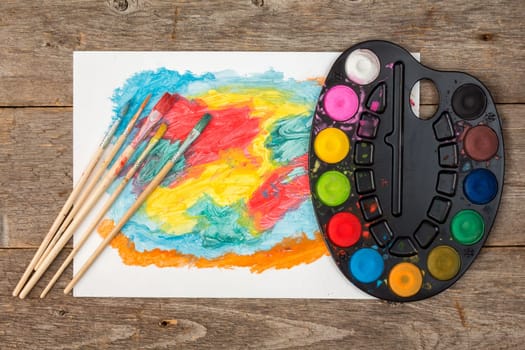 Abstract painting and watercolor palette on the old table. View from above
