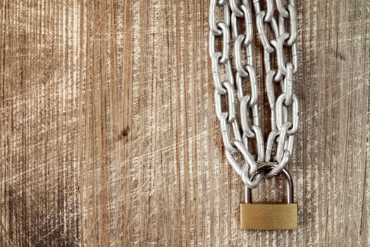 Padlock with chains on the old wooden background
